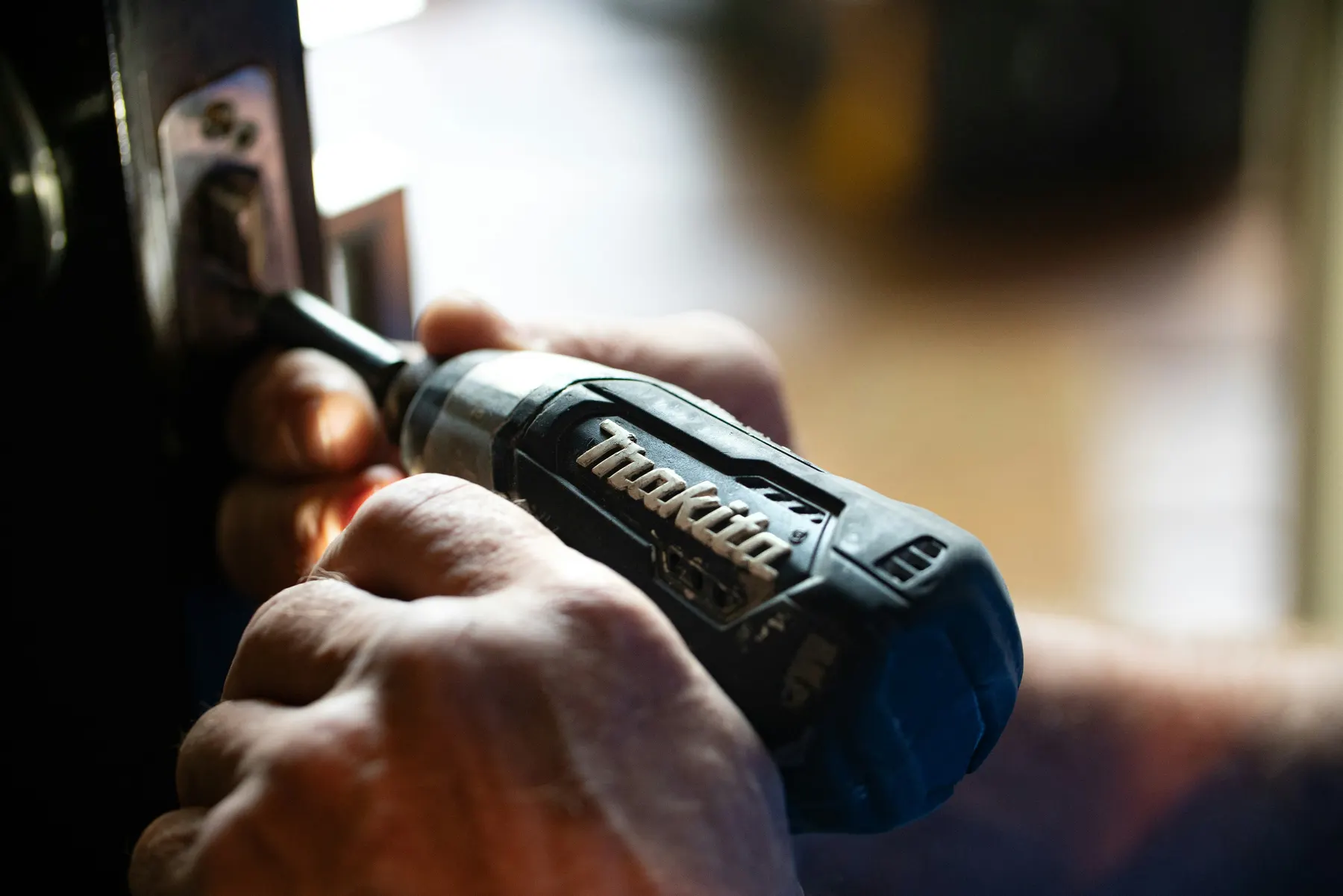 A licensed electrician's hands at work with a compact driver