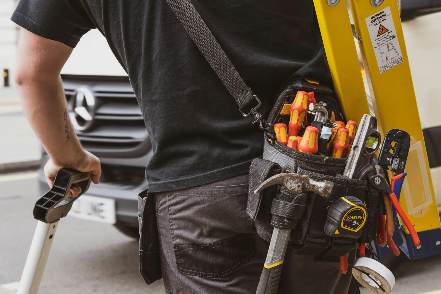 An electrician's loaded tool bag beside the work van